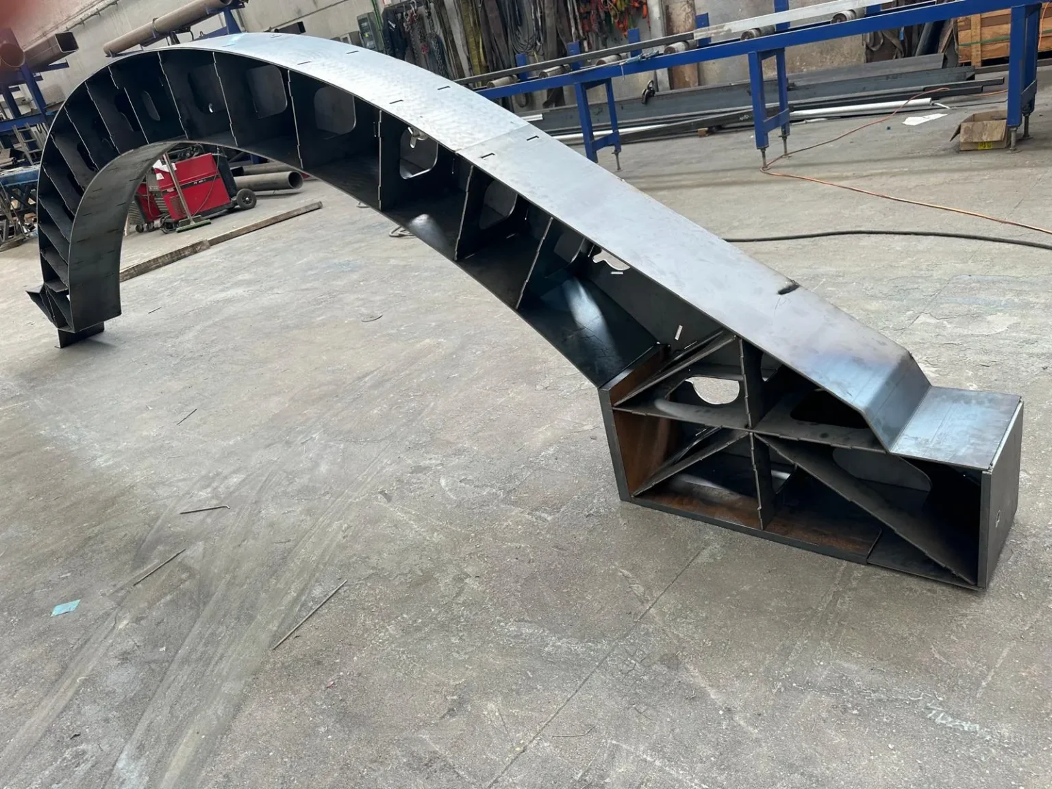 Arco sencillo de utillaje aeronáutico: viga curva en chapa de acero soldada, con base de anclaje rigidizada.