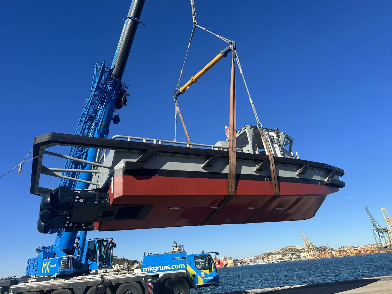Puesta a flote de una empujadora: izado con grúa en el muelle.